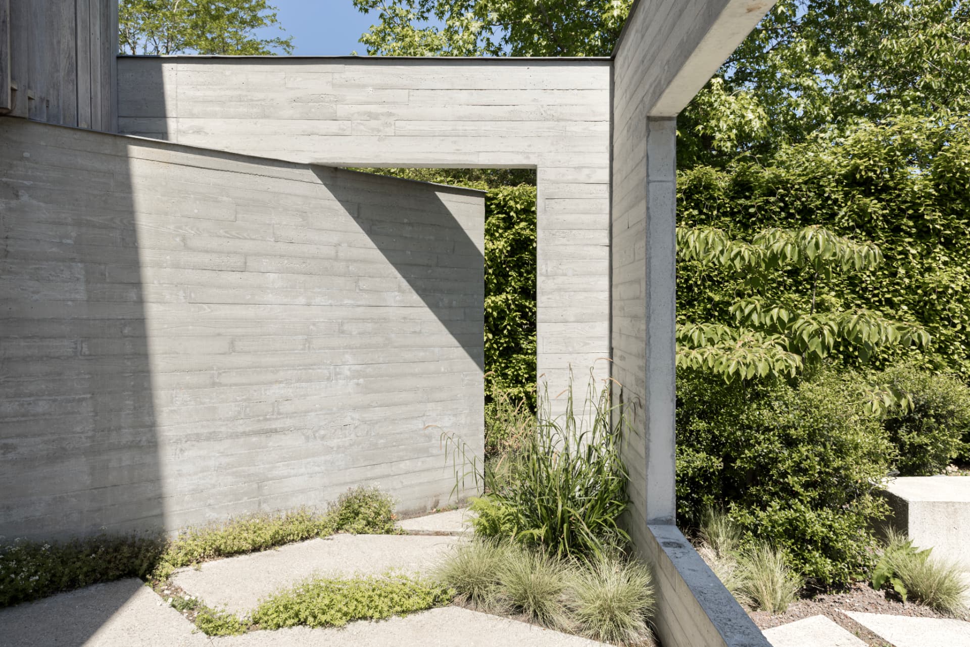 Garden path framed by concrete walls at OXfield