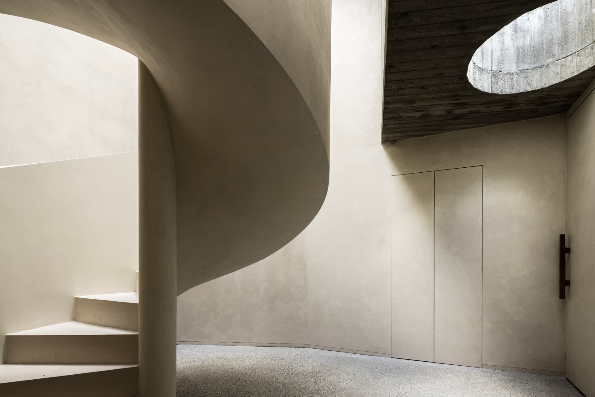Concrete stair and hallway with circular skylight at OXfield